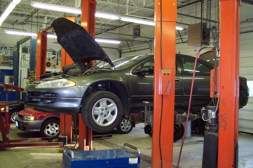 Dark gray Dodge Intrepid on a lift, hood open, with a red car visible below