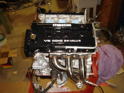 1993 Ford Probe - A Mazda V6 DOHC 24-valve engine is shown on a stand with chrome exhaust headers.