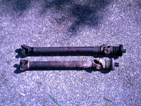 1987 Ford Bronco II - Two driveshafts are shown side-by-side on a gravel surface.