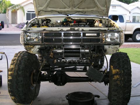 1986 Toyota Hilux - This modified 1986 Toyota Hilux features oversized tires and a front-mounted winch, with a second truck visible in the background.