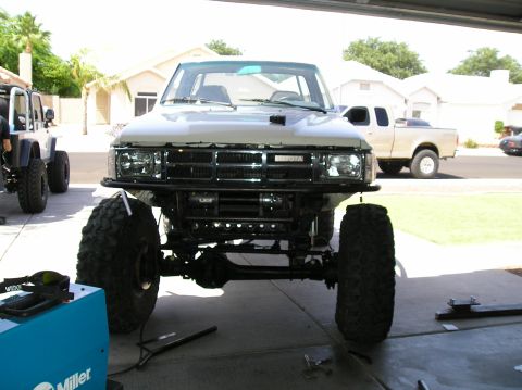 1986 Toyota Hilux - A modified Toyota pickup truck with a winch and oversized tires is parked in a garage.