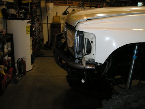 1986 Toyota Hilux - Front view of a white 1986 Toyota Hilux a custom bumper and winch mount, seen in a garage setting.