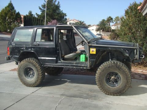1994 Jeep Cherokee - This modified 1994 Jeep Cherokee features an external roll cage and oversized tires, ready for off-road adventures.