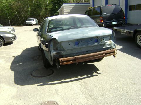 2001 Ford Crown Victoria - Rear view of a 2001 Ford Crown Victoria undergoing repairs, with other vehicles in the background.