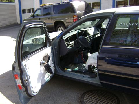 2001 Ford Crown Victoria - The interior of a car is exposed, with parts removed and the dashboard visible. Another vehicle is parked behind.