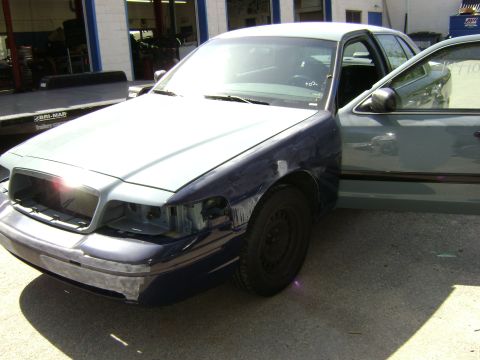 2001 Ford Crown Victoria - A 2001 Ford Crown Victoria is shown with damage to its front end and an open driver's door.