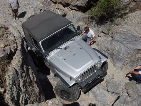 1986 Toyota Hilux - Jeep Wrangler tackling a challenging off-road trail with steep rock formations.