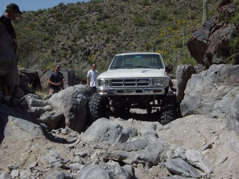 1986 Toyota Hilux - This modified Toyota pickup truck is carefully driven over a challenging rocky terrain in a desert environment.