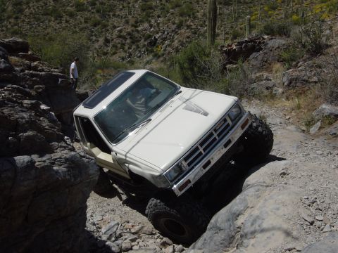 1986 Toyota Hilux - A white 1986 Toyota Hilux navigates a challenging rocky trail, its off-road capabilities.