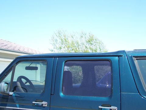 1995 Ford C-150 (Centurion Conversions) - Side view of a teal van's interior, showing the steering wheel and door handle. The body style indicates it is likely a 1992 model.
