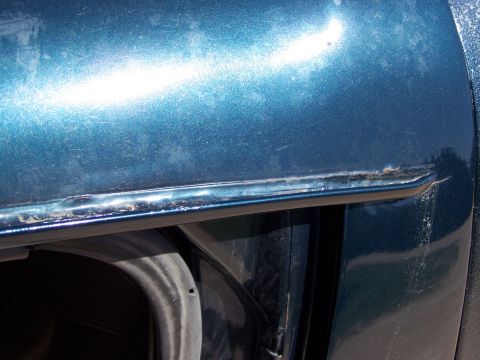 1995 Ford C-150 (Centurion Conversions) - Detail of a car's door edge shows signs of wear and corrosion.