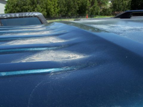 1995 Ford C-150 (Centurion Conversions) - Dented truck bed cover shows damage.