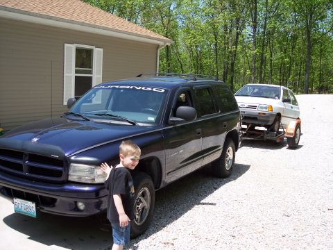2007 Dodge Durango - A Dodge Durango is parked next to a house, towing a small white car on a trailer.