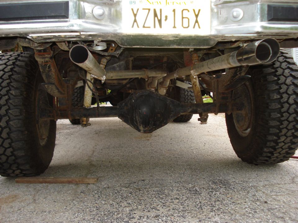 Rear view of a pickup truck showing the axle, dual exhaust pipes, and New Jersey license plate XZN-16X