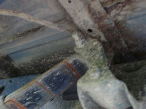 1981 Ford F-250 - Close-up view of the heavily corroded undercarriage of a vehicle, showing structural components and accumulated dirt.