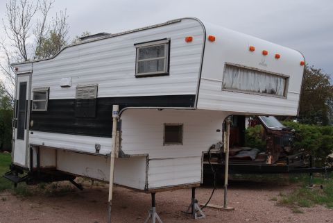 1987 Ford F-250 - A camper unit is supported by jack stands, with a trailer frame partially visible.