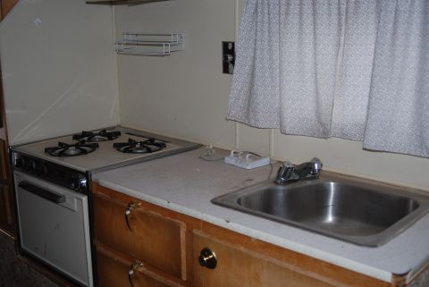 1987 Ford F-250 - Interior view of a camper kitchen area, showing a stove, sink, and cabinetry.
