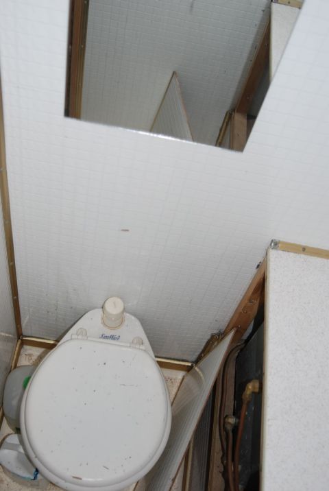 1987 Ford F-250 - Interior view of a camper's toilet area, showing plumbing and wall paneling.