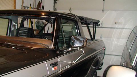1979 Ford Bronco - A two-tone Ford Bronco is visible from the side in a garage, with a roll bar and soft top.
