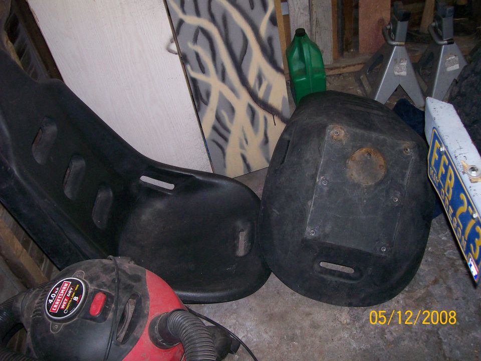 Two black plastic seats, a red shop vac, and a green gas can in a cluttered garage