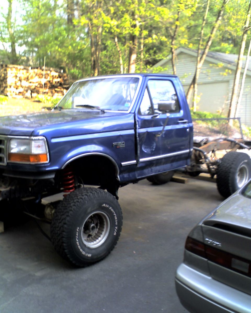 Blue 1996 Ford F-150 chassis with lifted suspension and large tires
