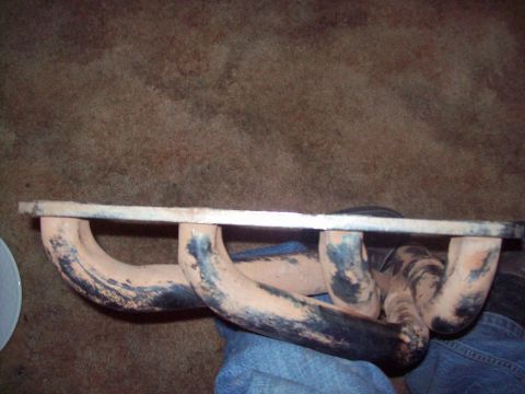 1984 Ford Bronco - Exhaust manifold part shown from above, resting on a blue fabric surface.
