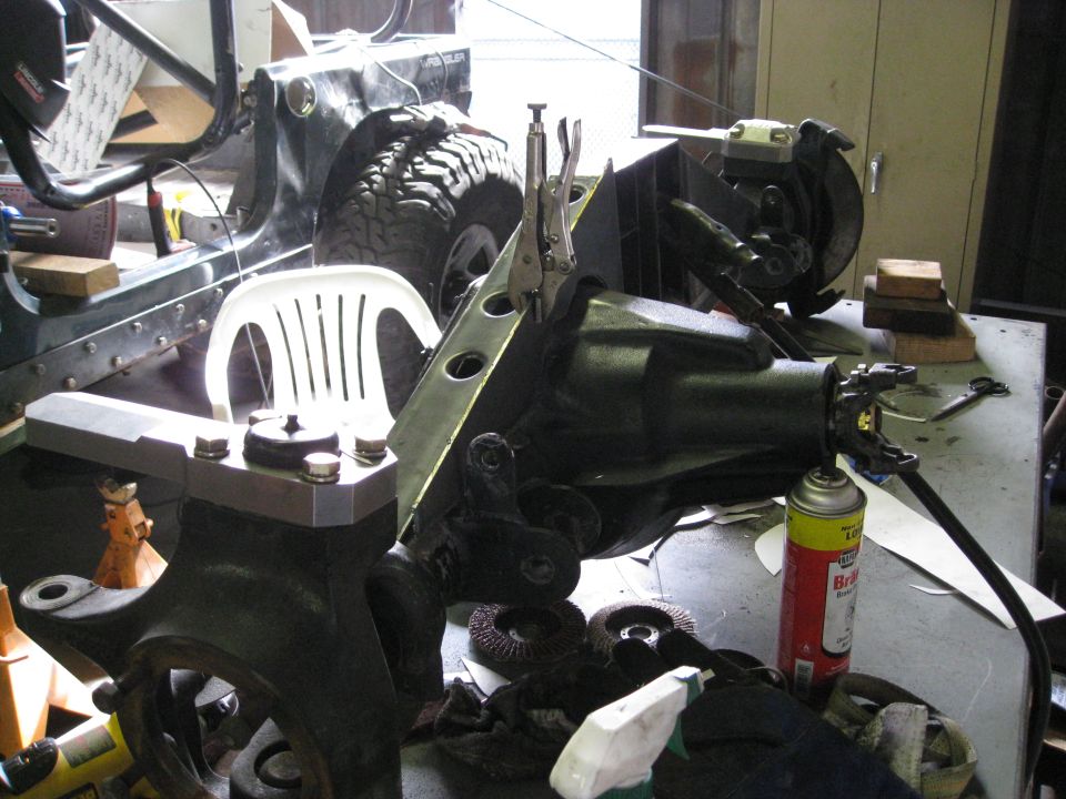 Jeep YJ front axle assembly on a workbench with vice grips and a can of brake cleaner