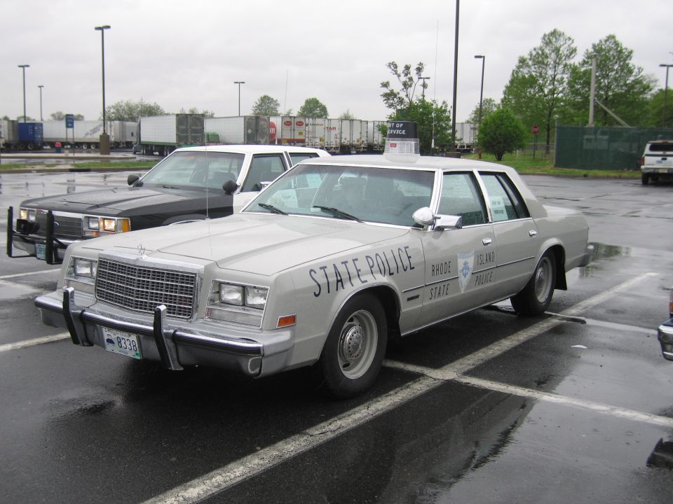 Silver Rhode Island State Police sedan with push bar on wet parking lot