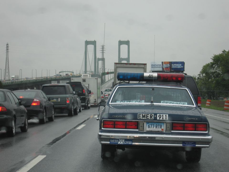 Rear of blue Chevrolet Caprice EMER-911 cruiser on rainy highway