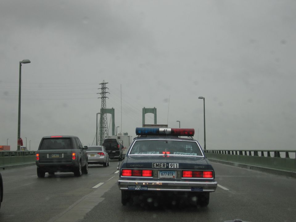 Rear of dark Chevrolet Caprice cruiser on bridge roadway in rain