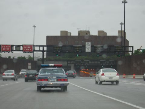 1991 Ford LTD Crown Victoria - dark police cruiser and traffic approach tunnel entrances with overhead Do Not Enter and tunnel-traffic lane signs.