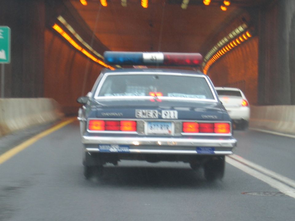 Rear of dark Chevrolet Caprice cruiser driving inside lit tunnel