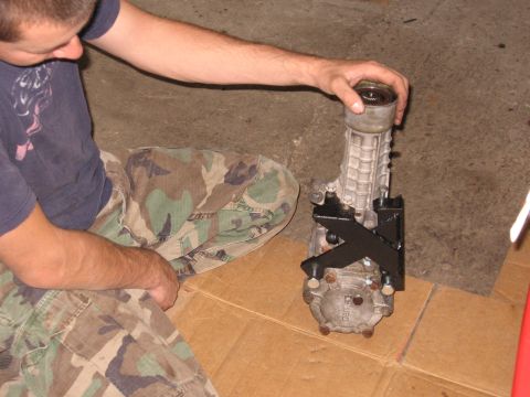 1991 Mitsubishi 3000GT - Transfer case assembly being held by a person, likely for repair or installation.