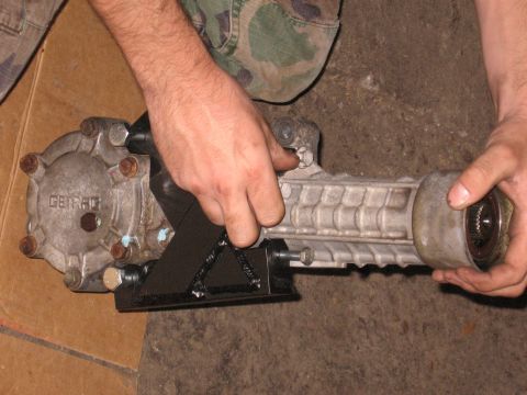 1991 Mitsubishi 3000GT - A close-up shows a Getrag differential being held by two hands, with a black metal bracket attached.