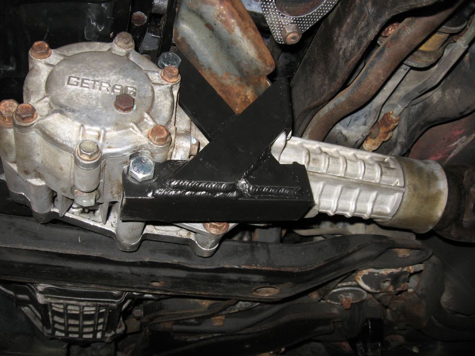 Getrag-marked aluminum housing under car resting on welded steel support arm