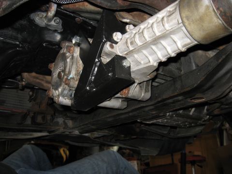 1991 Mitsubishi 3000GT - Close-up view of a vehicle's underbody drivetrain components, a black bracket installed on the transmission.