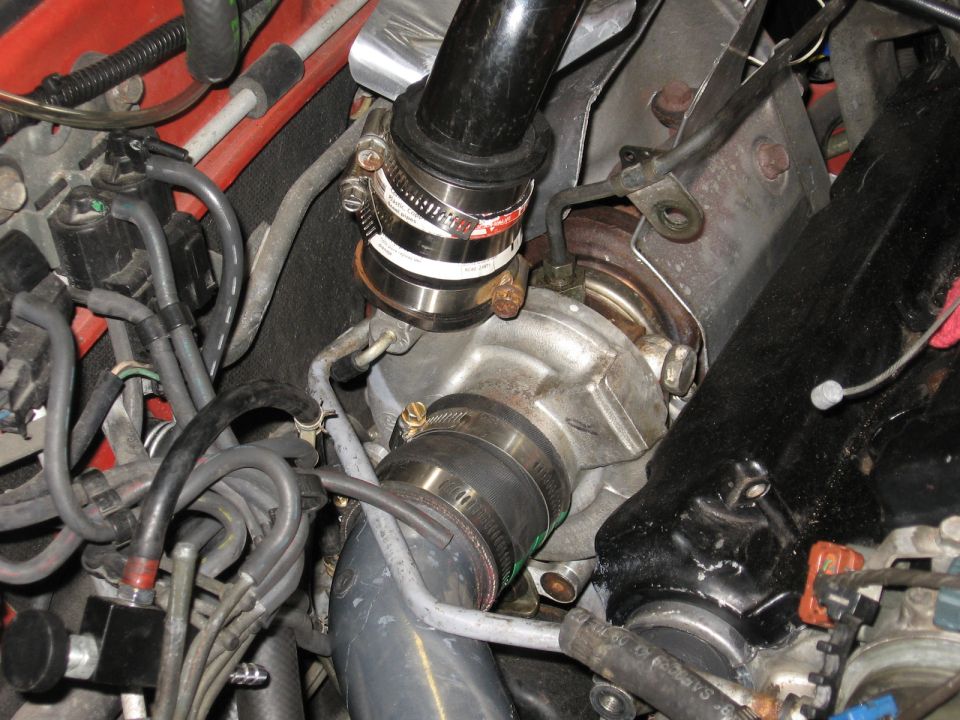 Close-up of a turbocharger with intake piping and various hoses connected