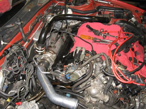 1991 Mitsubishi 3000GT - The engine bay of a car is shown with various components and tools laid out on a red cloth.