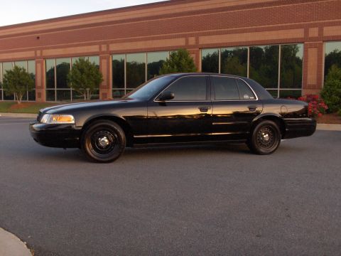 2001 Ford Crown Victoria - Side view of a black 2001 Ford Crown Victoria parked outside a commercial building.