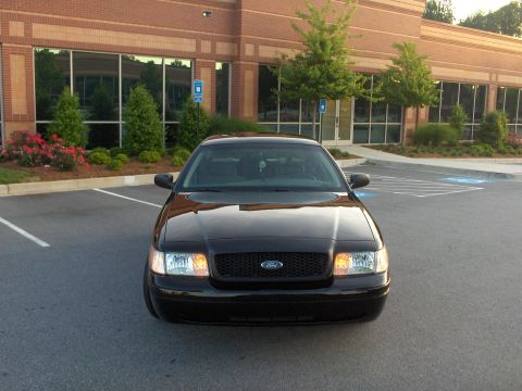 2001 Ford Crown Victoria - A black 2001 Ford Crown Victoria is parked in front of a brick building.