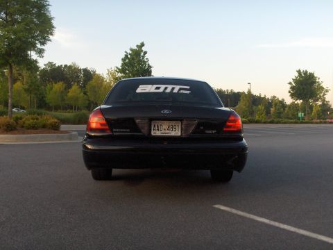 2001 Ford Crown Victoria - Rear view of a black Ford Crown Victoria with a sticker on the rear window and a license plate.