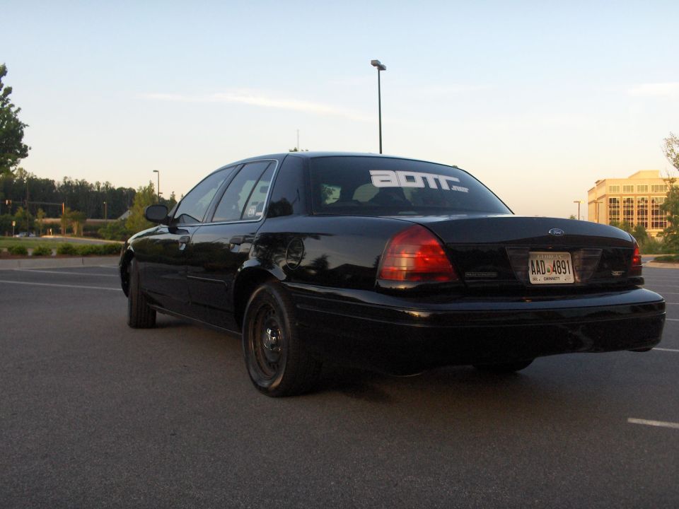 Black 2001 Ford Crown Victoria with ADTT.net sticker on rear window, parked in a lot.