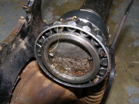1993 Ford Bronco - A close-up view shows a heavily soiled wheel bearing assembly attached to a rusty metal component, possibly from a 1993 Ford Bronco.