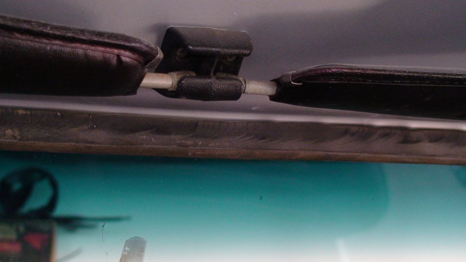 Close-up of a car's sun visor mechanism and the top of the windshield.