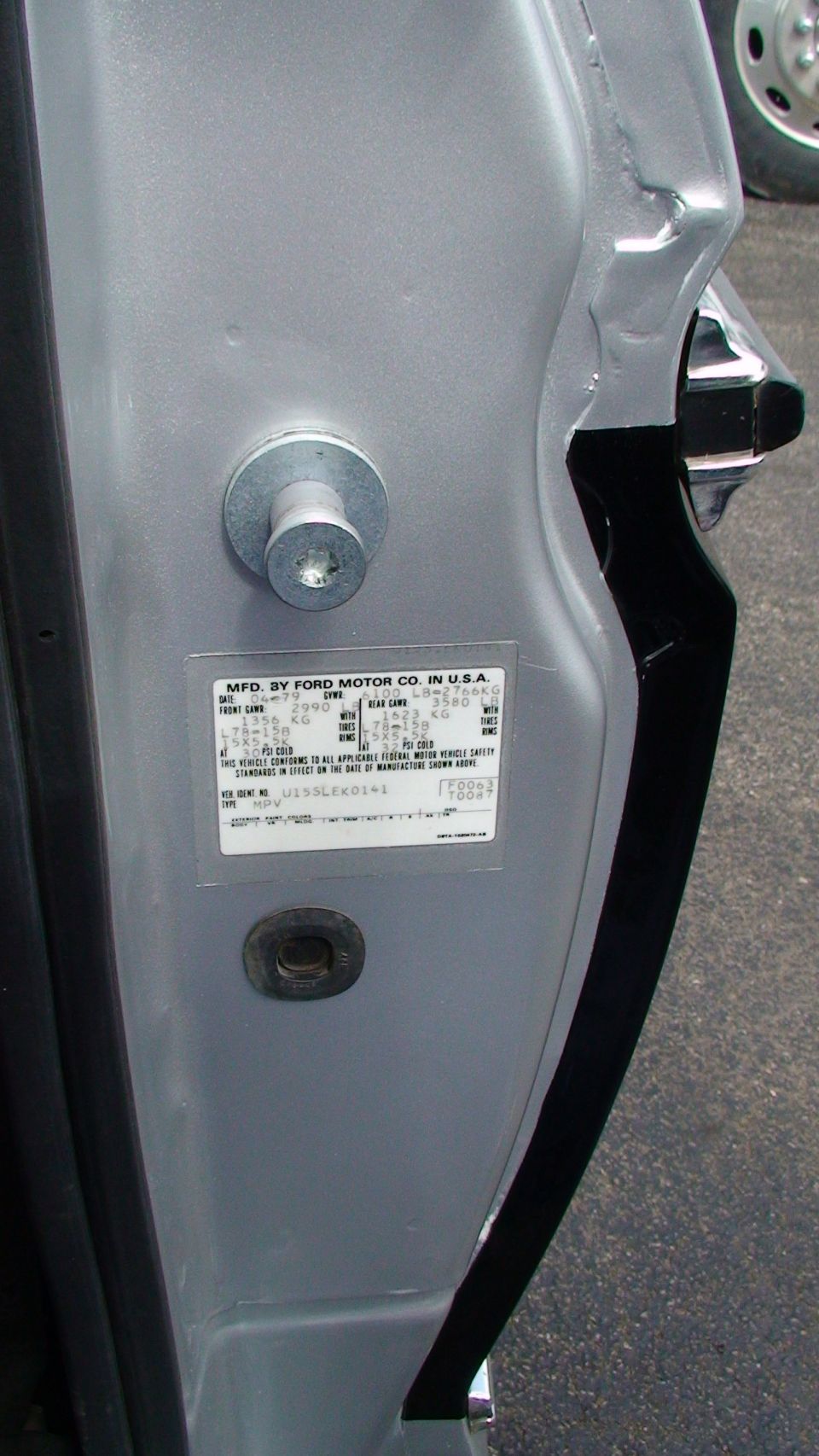 Ford door jamb certification label below the door striker on a silver door