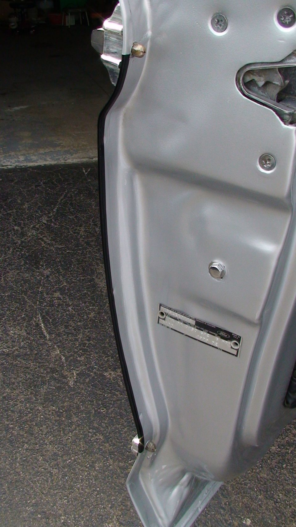 Close-up of a silver vehicle's door jamb, showing a VIN plate and door seal