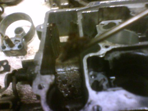 1993 Ford Bronco - Internal view of a carburetor, showing grime and a tool being used for cleaning or repair.