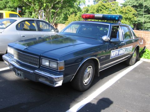1991 Ford LTD Crown Victoria - dark blue North Haven Police Chevrolet Caprice sedan with red and blue roof light bar parked on a sunny lot.