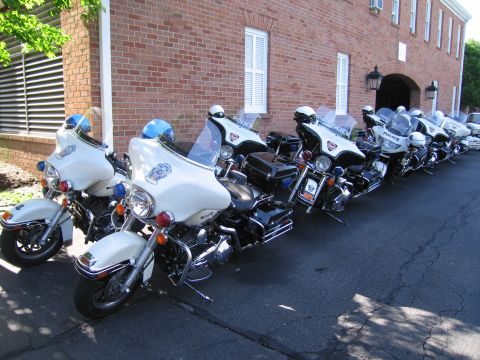 1991 Ford LTD Crown Victoria - long row of white and black police motorcycles parked diagonally along the side of a brick building.