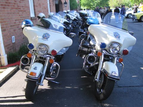 1991 Ford LTD Crown Victoria - Two white police Harley-Davidson motorcycles with fairings and blue lights parked facing each other near a brick wall.